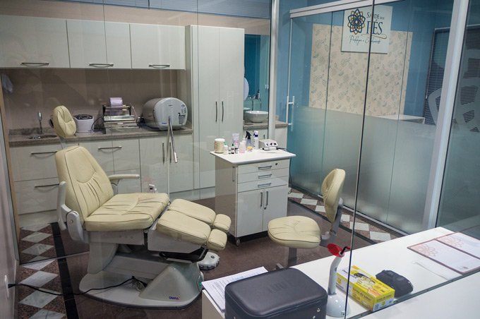 Sala de atendimento com cadeira de podologia reclinável e divisória de vidro